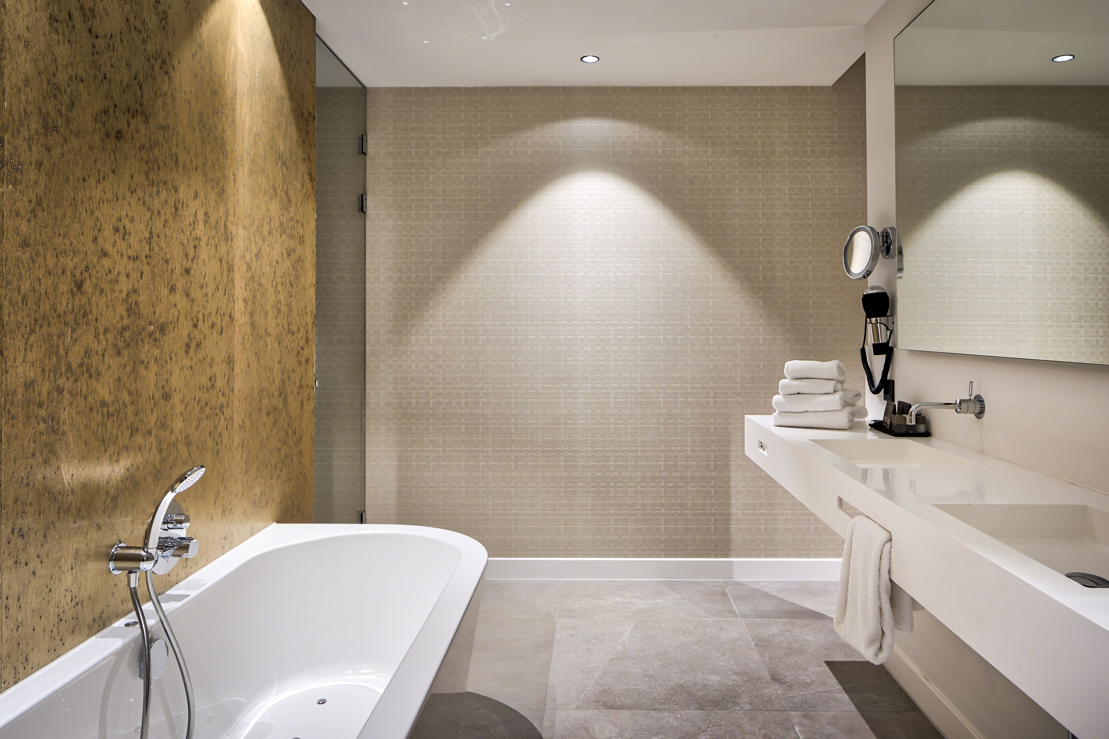 Une salle de bain moderne avec une baignoire sur pieds, un meuble-lavabo avec un miroir et un porte-serviettes.
