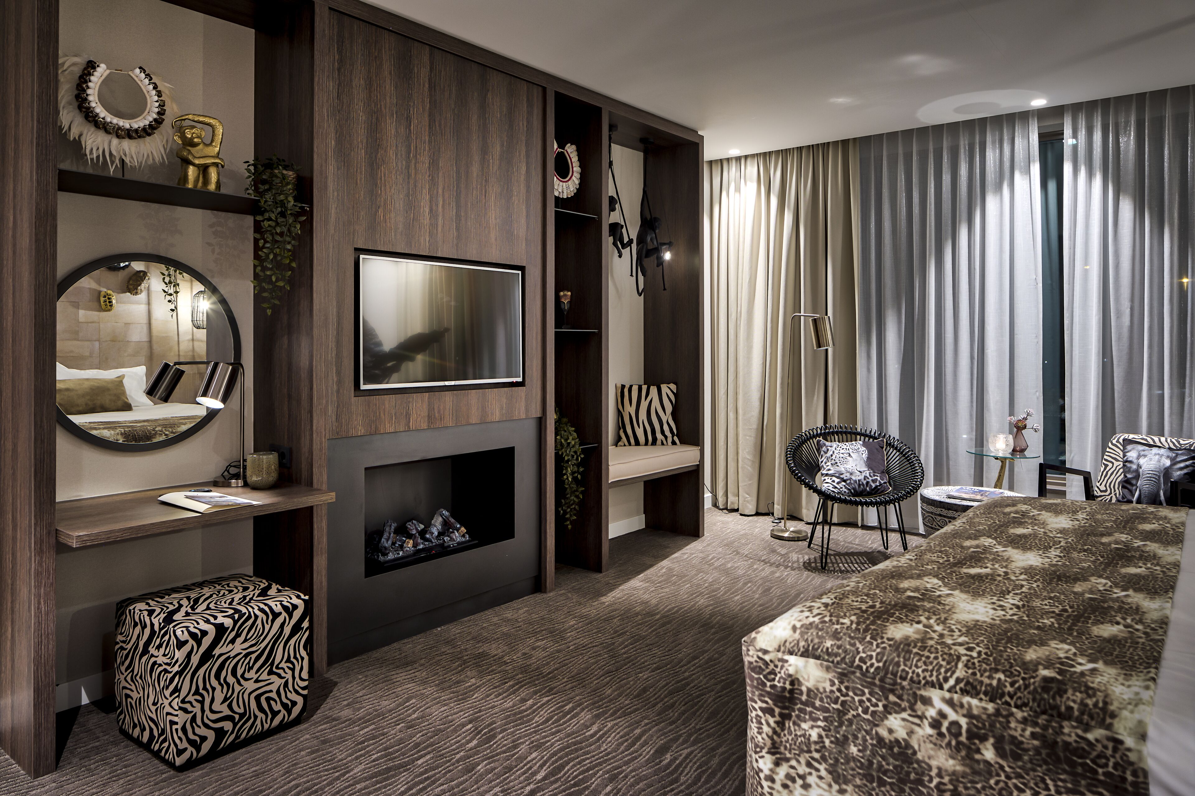 Une chambre d’hôtel moderne dotée d’une cheminée, d’un téléviseur à écran plat, d’un canapé et d’un coin repas.