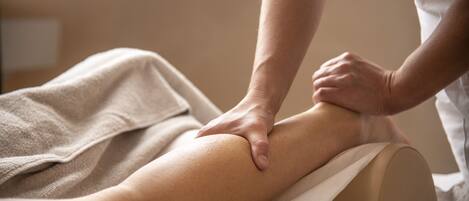 A person receiving a massage on a massage table with a towel and a massage cushion.
