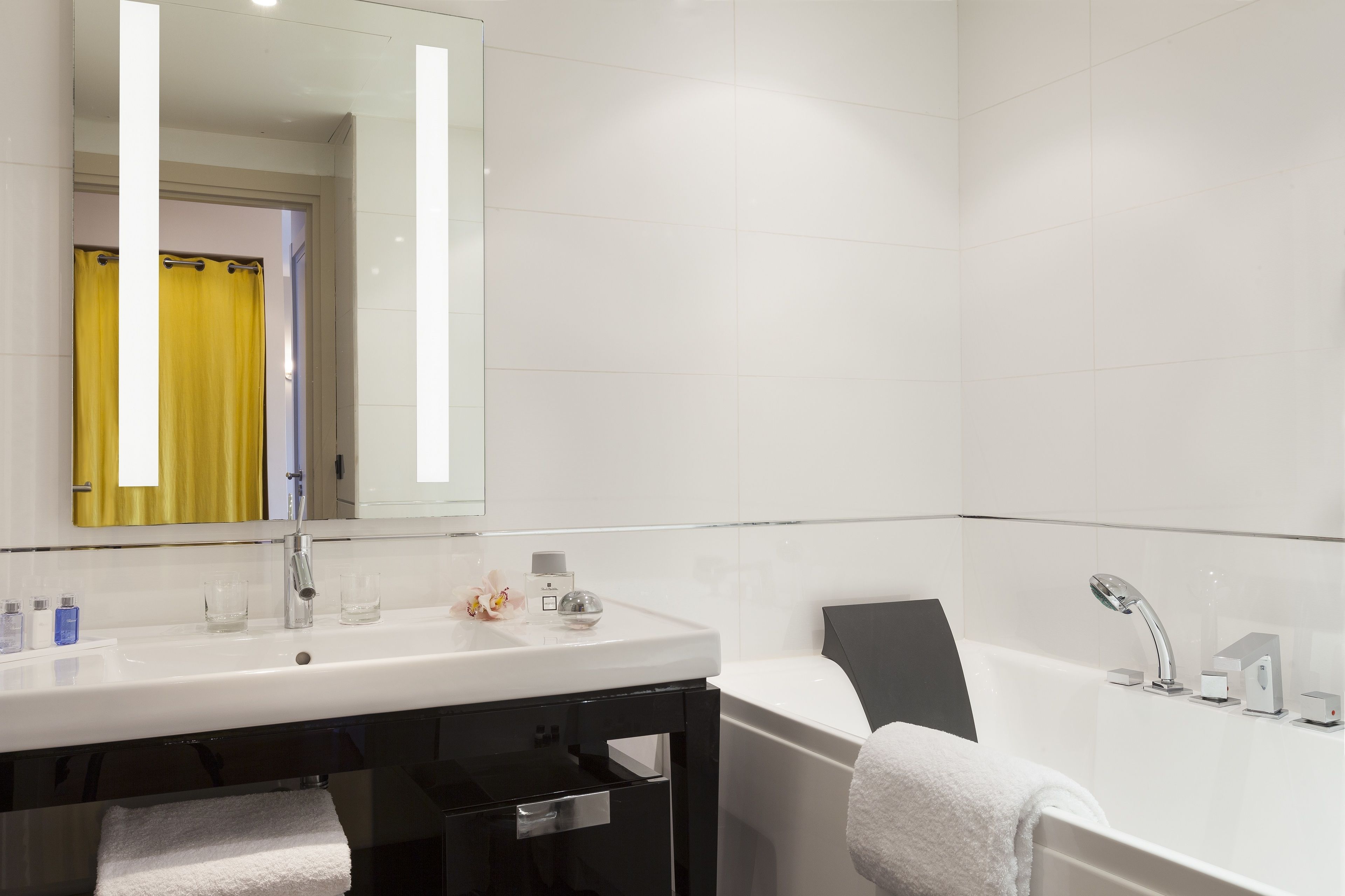 Un baño moderno con un lavabo, espejo y bañera blancos.