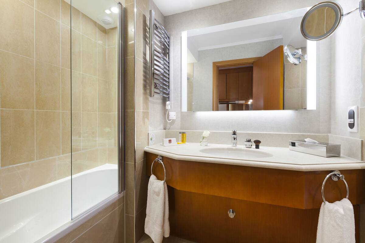 A modern bathroom with a glass shower enclosure, a vanity with a sink and mirror, and a towel ring.