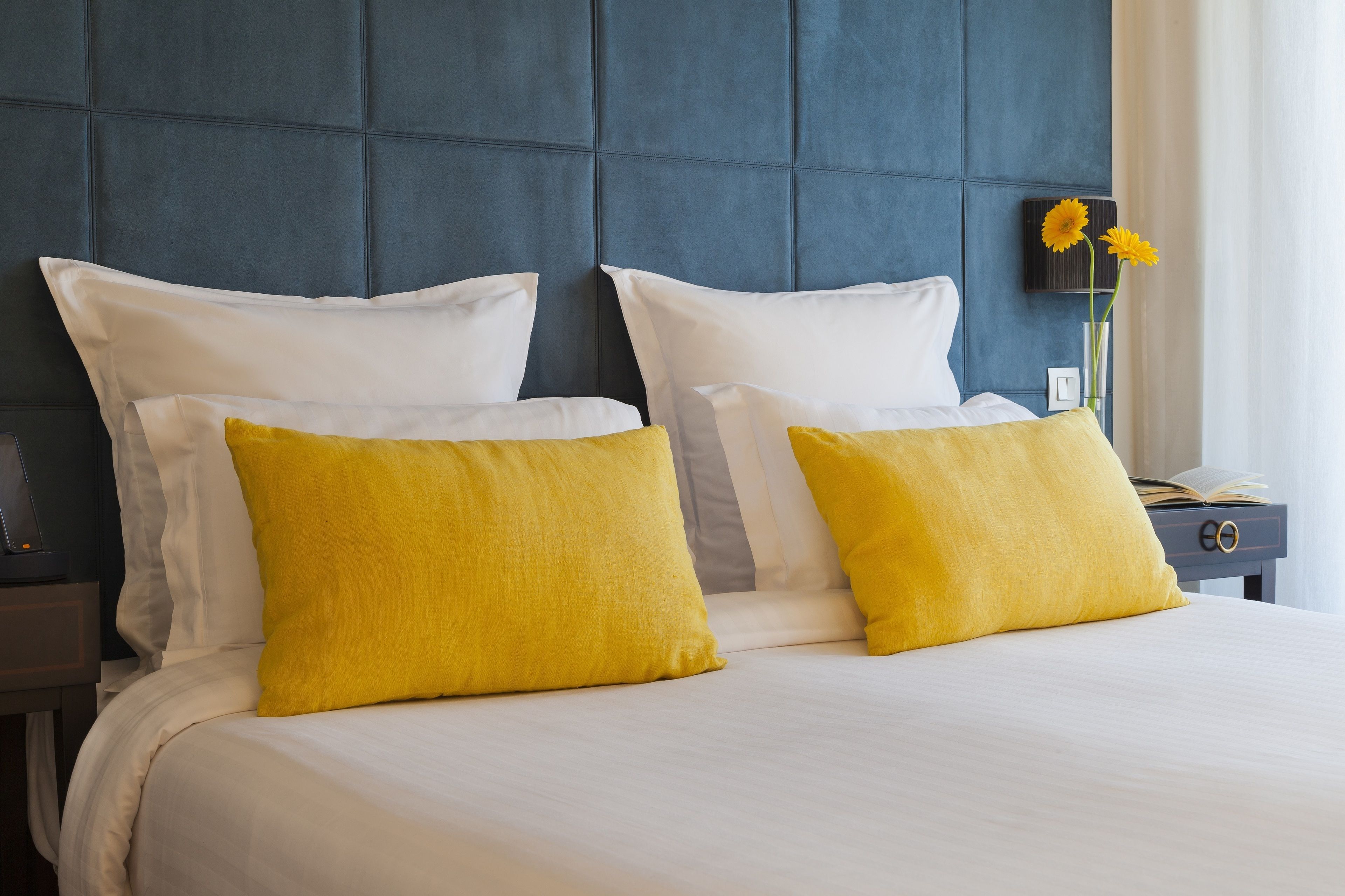Ein Hotelzimmer mit einem großen Bett, zwei weißen Kissen und zwei gelben Kissen.
