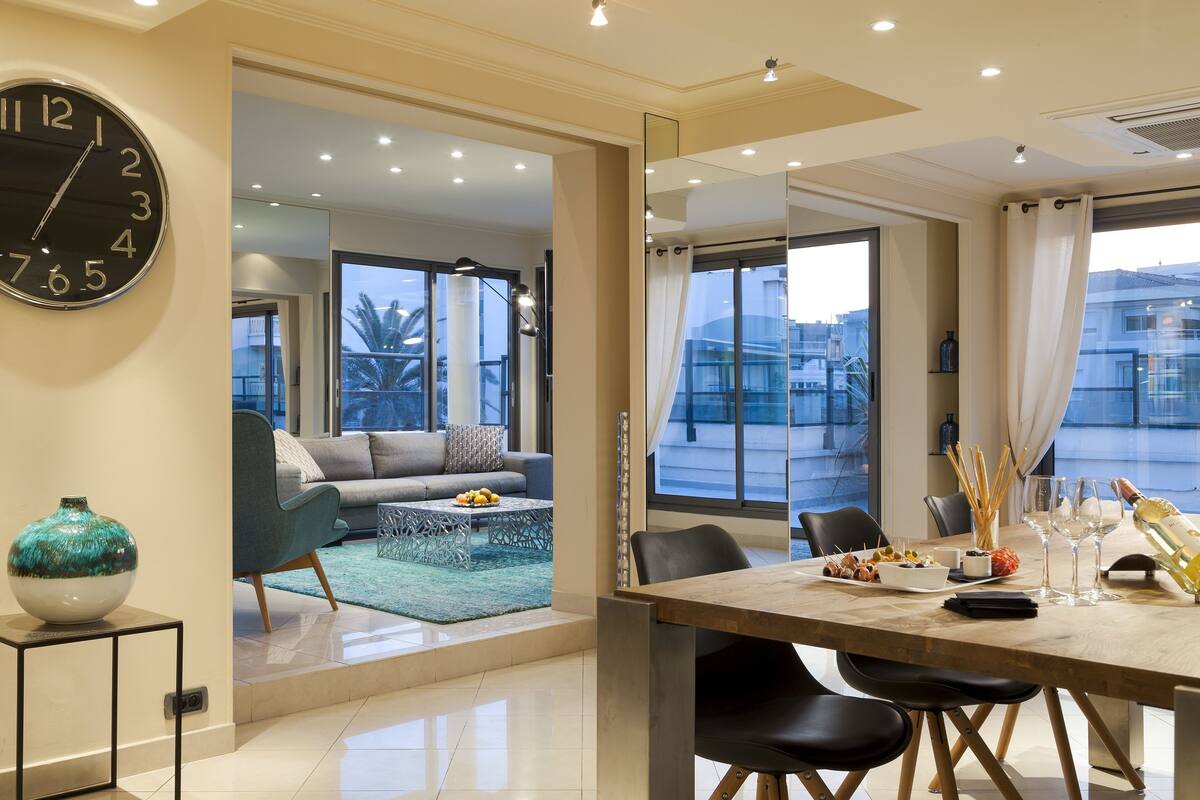 A modern dining area with a large table, chairs, and a view of the outside.