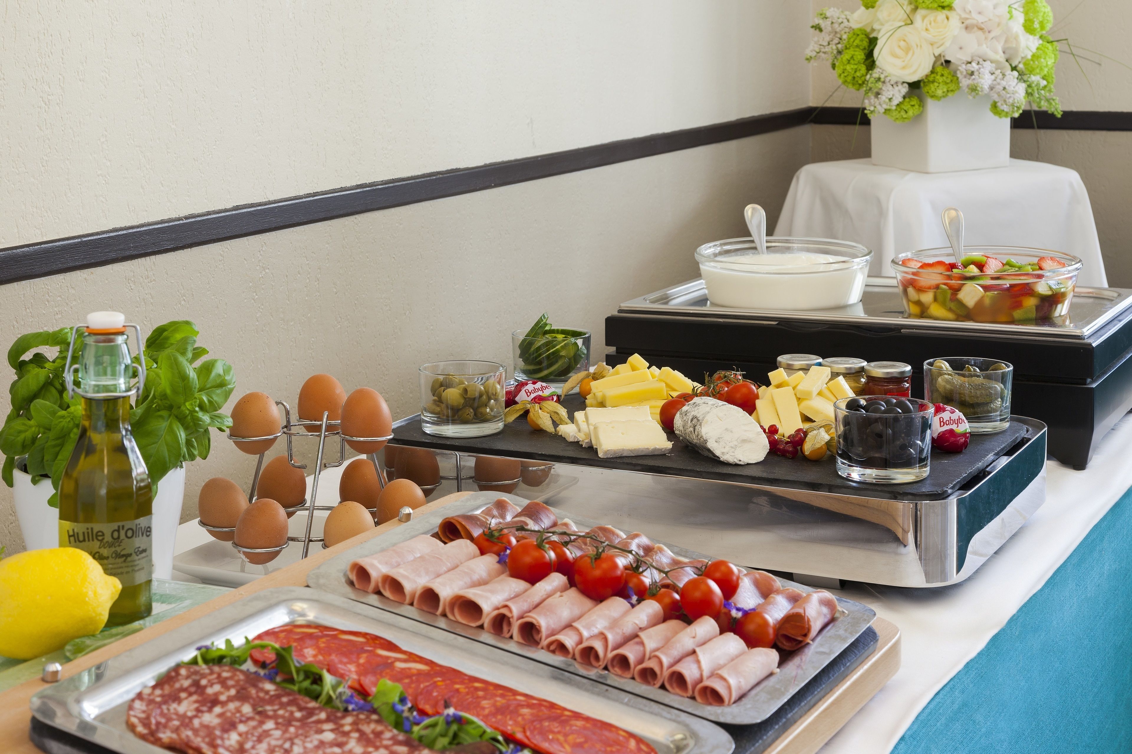 A buffet table with various food items including eggs, cheese, meats, and a salad.