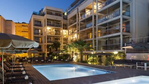A multi-story hotel with a swimming pool, outdoor seating, and balconies. - Nehô Suites Cannes Croisette (Cannes)