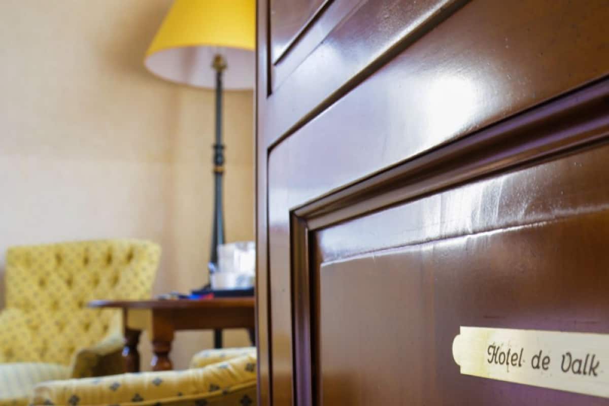 Een houten deur met een bord waarop 'Hotel de Valk' staat.