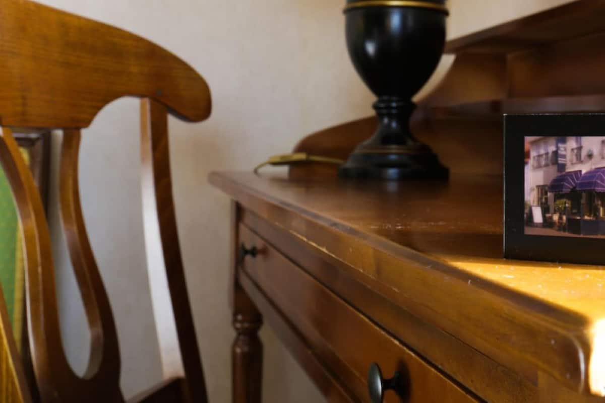 Een houten stoel, een tafel met een lamp en een ingelijste foto op de tafel.