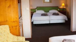A hotel room with a double bed, a wooden wardrobe, a green headboard, a framed picture on the wall, and a bedside lamp. - Hotel De Valk (Westkapelle)