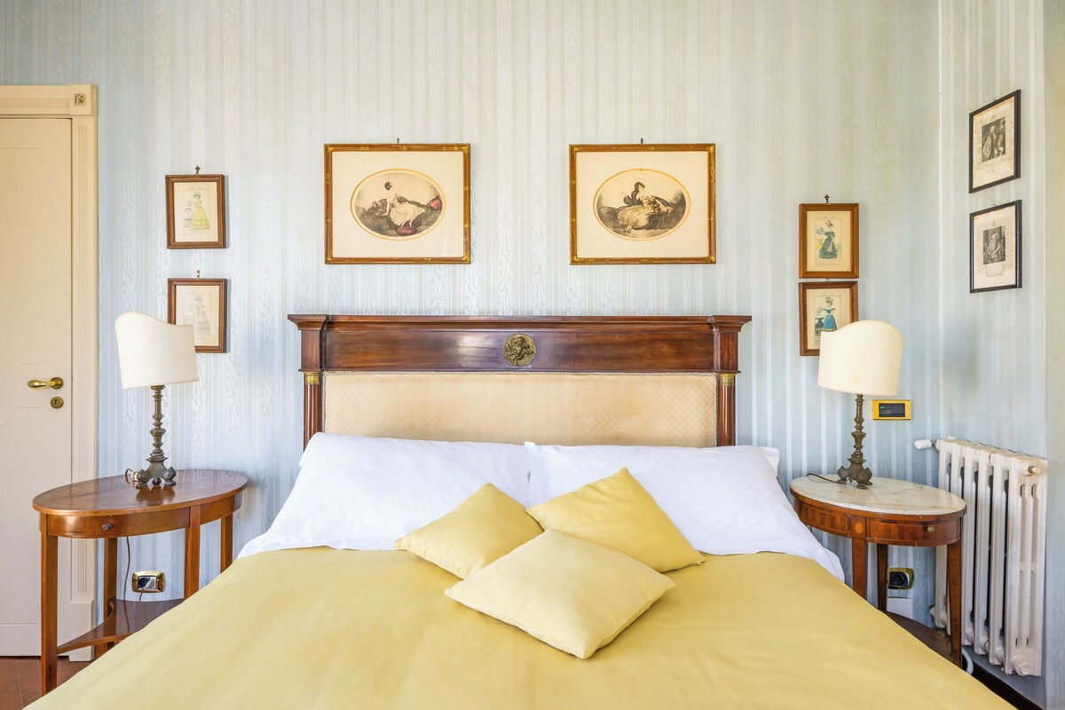 Una cama bien hecha con dos almohadas, un cabecero de madera y dos mesitas de noche con lámparas.