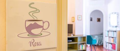 A wall with a framed artwork of a cup with steam, labeled "Rosa".