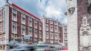 Un edificio grande de varios pisos, con techo rojo y un letrero llamativo a la izquierda.