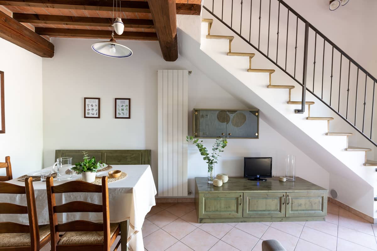 A dining area with a table set for two, a green cabinet, and a staircase.
