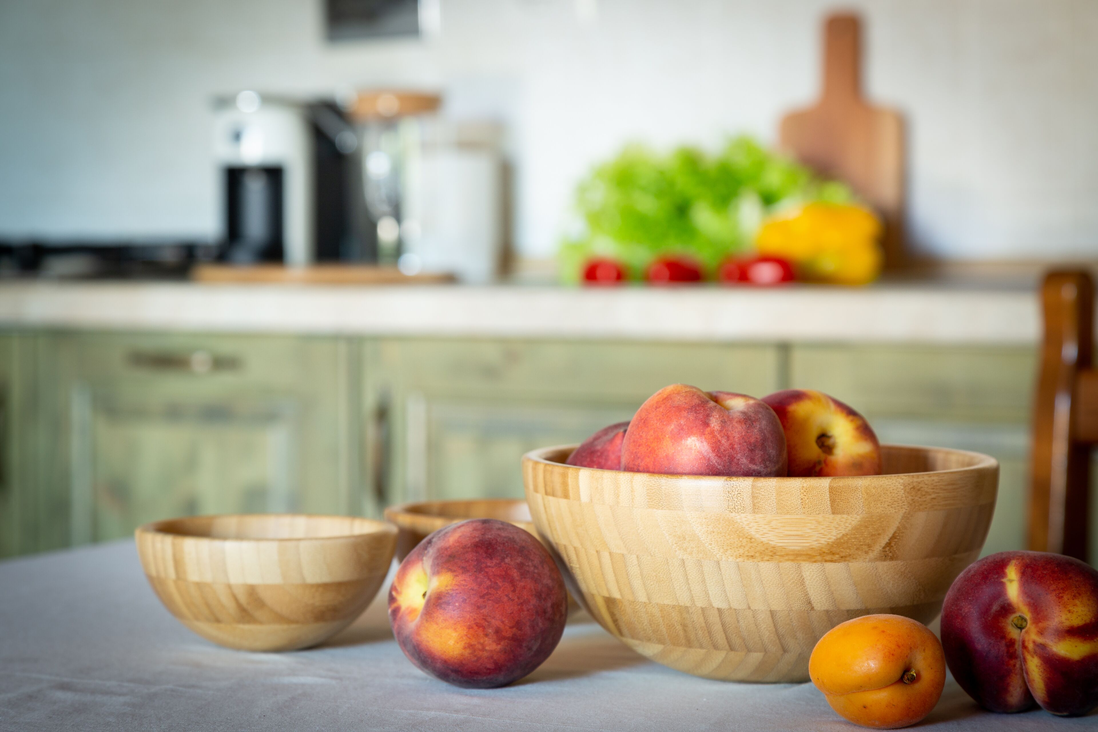 A kitchen with wooden bowls containing fruits, a coffee maker, and a fruit bowl on the counter.