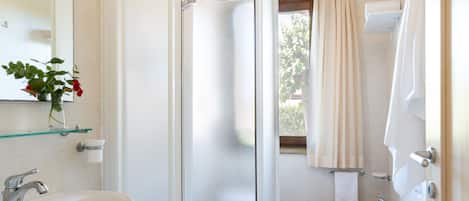 A bathroom with a glass-enclosed shower, a sink, a toilet, and a mirror.