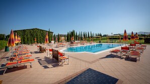 A poolside area with lounge chairs and umbrellas, a swimming pool, and a landscaped garden. - Borgo Verde (Rosignano Marittimo)