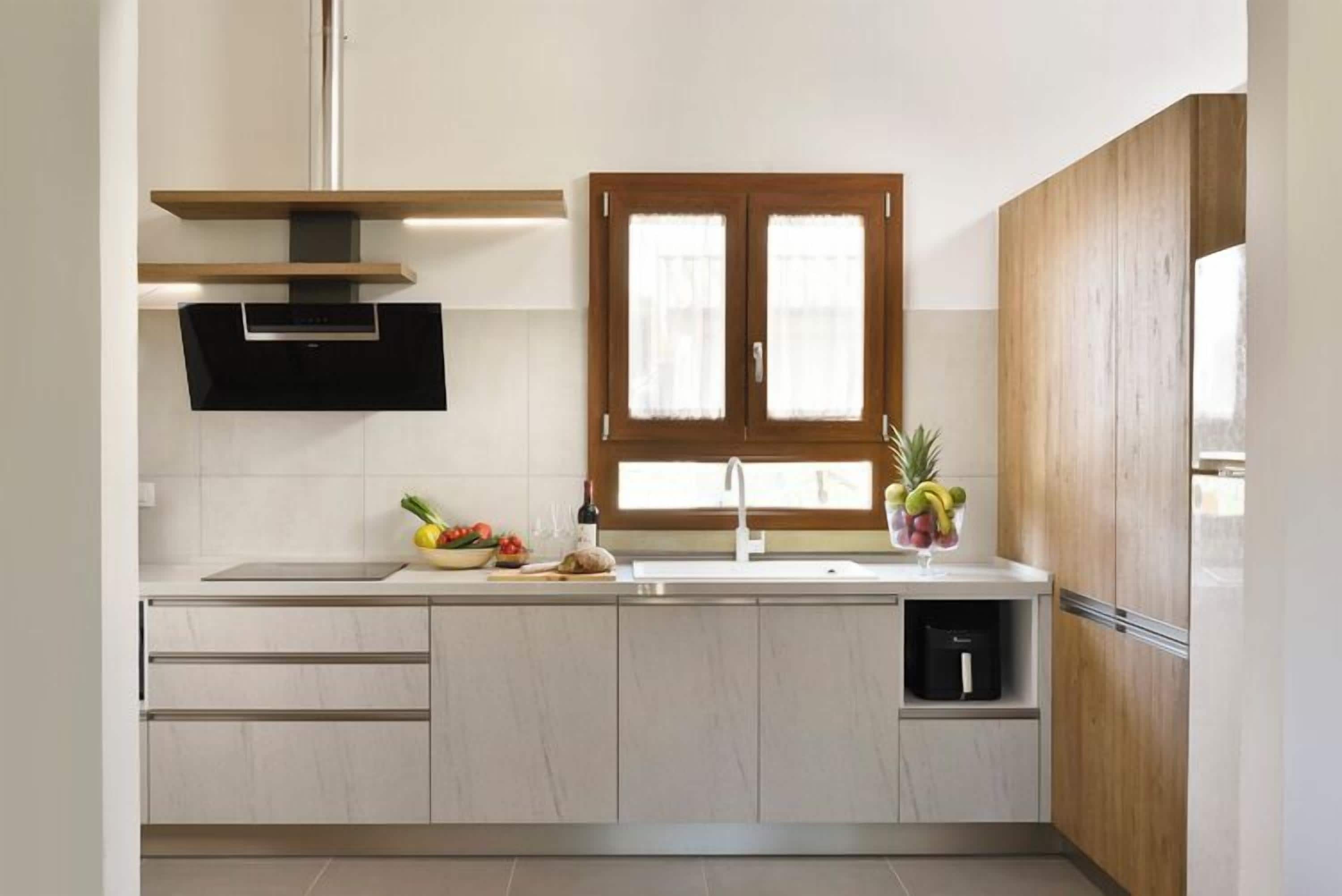 A modern kitchen with a built-in stove, a window with wooden shutters, and a sink.