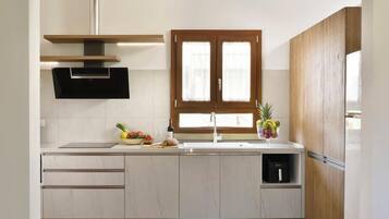 A modern kitchen with a built-in stove, a window with wooden shutters, and a sink.