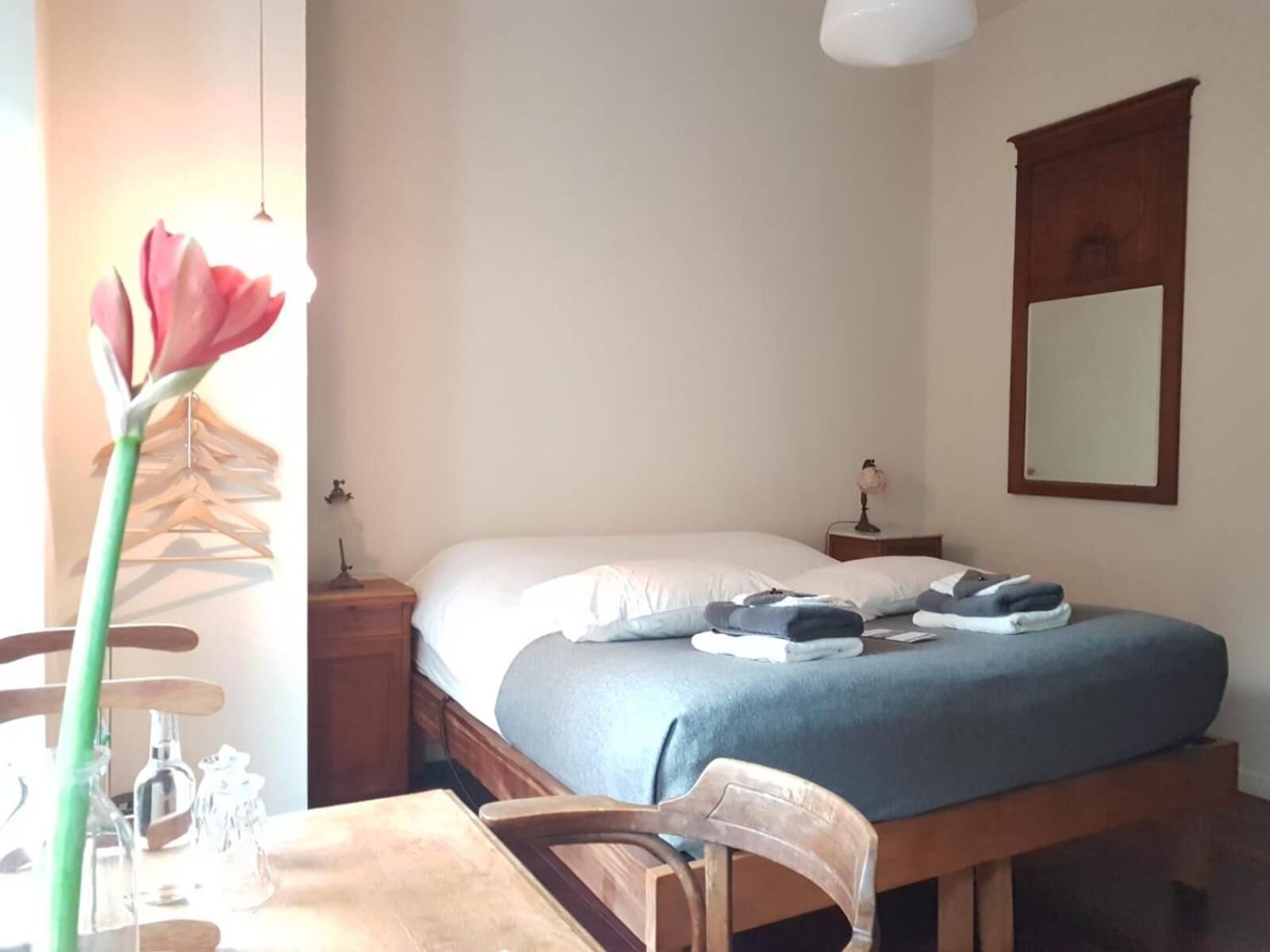 Een slaapkamer met een bed, nachtkastjes, een stoel, een tafel en een hangplant.