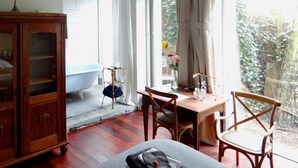 Een badkamer met een vrijstaand bad, een houten kast en een tafel met stoelen.