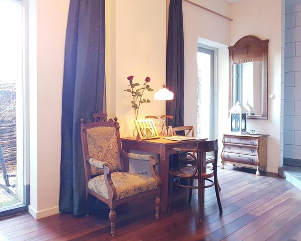Un comedor con una mesa de madera, dos sillas, un florero con flores y una lámpara.