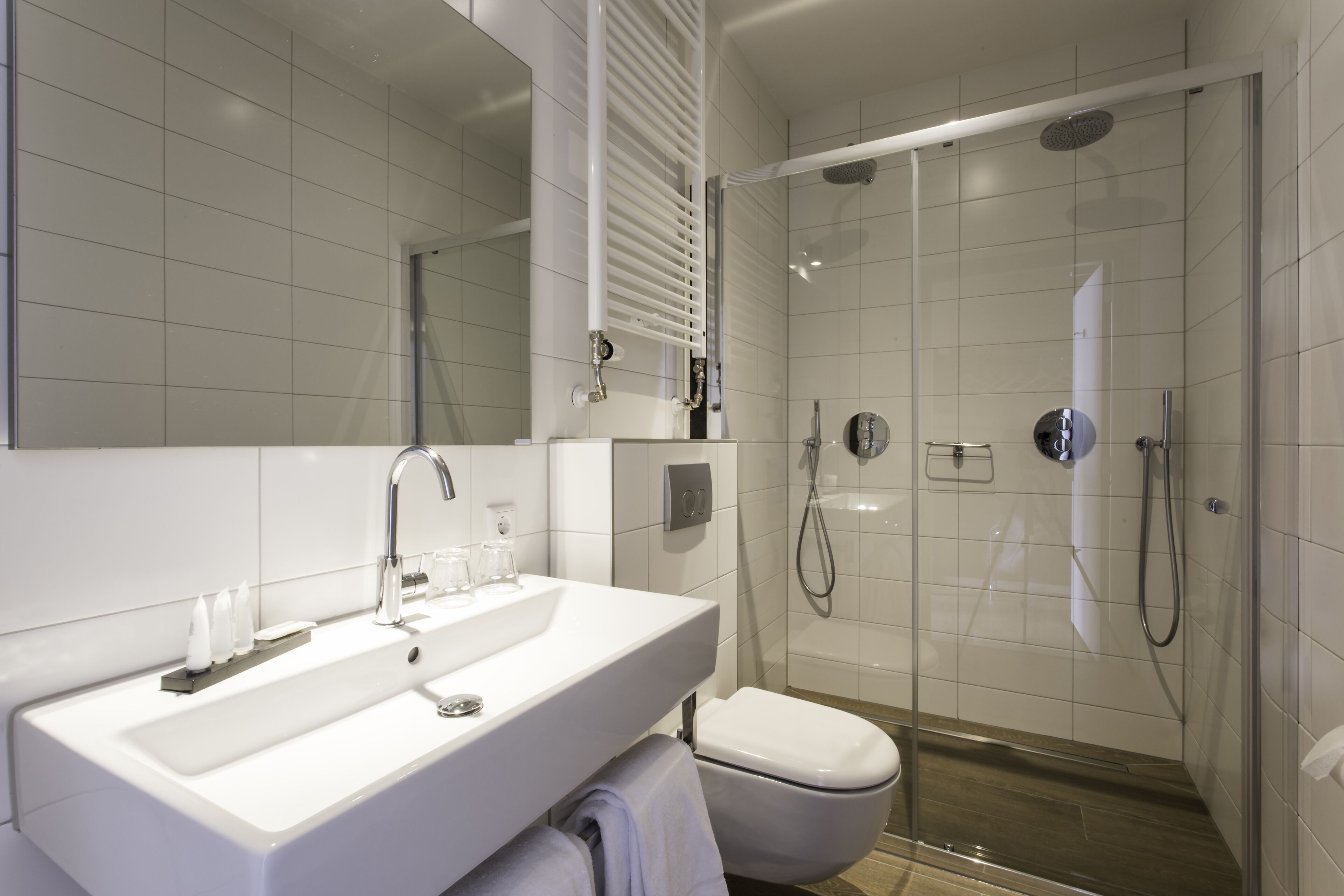 A modern bathroom with a white sink, mirror, and glass-enclosed shower.