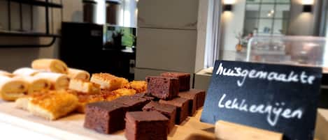 A dessert display with various sweets and a sign that reads "huisgemaakte lekkernijen".