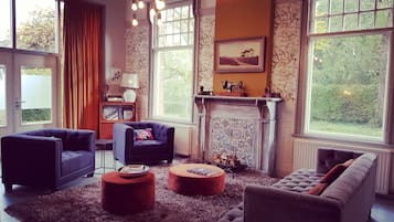 Uma sala de estar acolhedora com lareira, dois sofás, uma mesa de centro e uma televisão antiga.