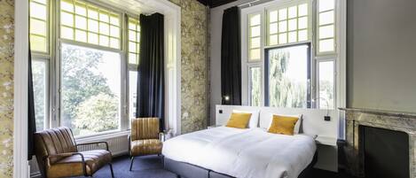 Una camera da letto con un letto grande, due poltrone e un camino.