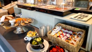A buffet area with various food items, including a bowl of soup, a basket of pastries, and a tray of sandwiches. - Rijksmonument Hotel de Sprenck (Middelburg)