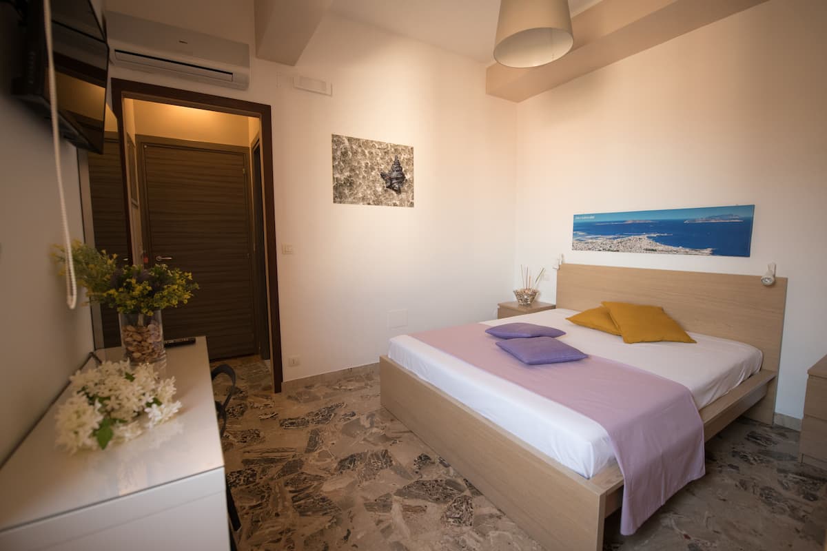 A bedroom with a bed, a nightstand, a dresser, and a painting on the wall.