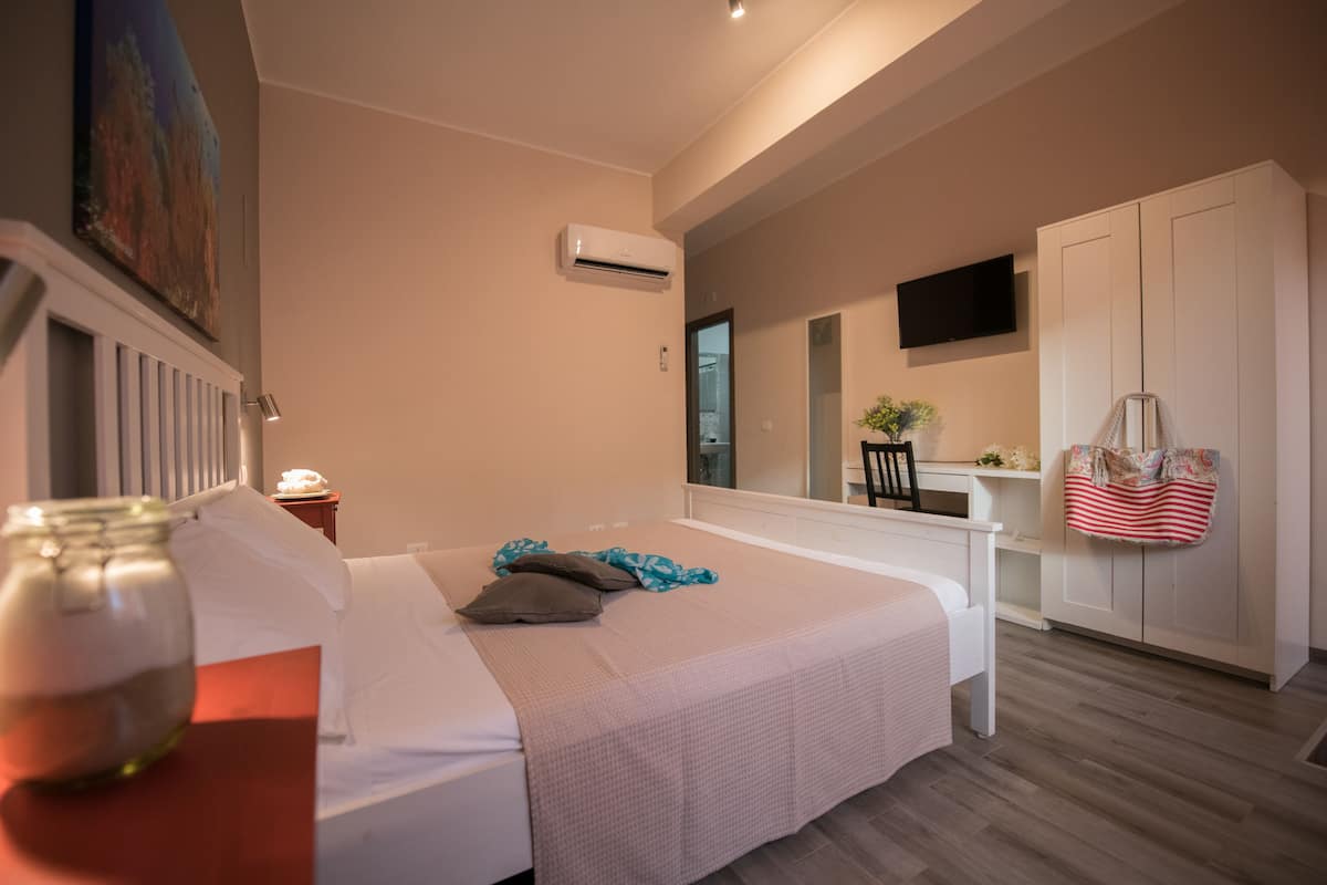 A bedroom with a bed, bedside table, and a mirror.