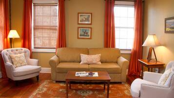 A living room with a beige sofa, two armchairs, a coffee table, and two lamps.