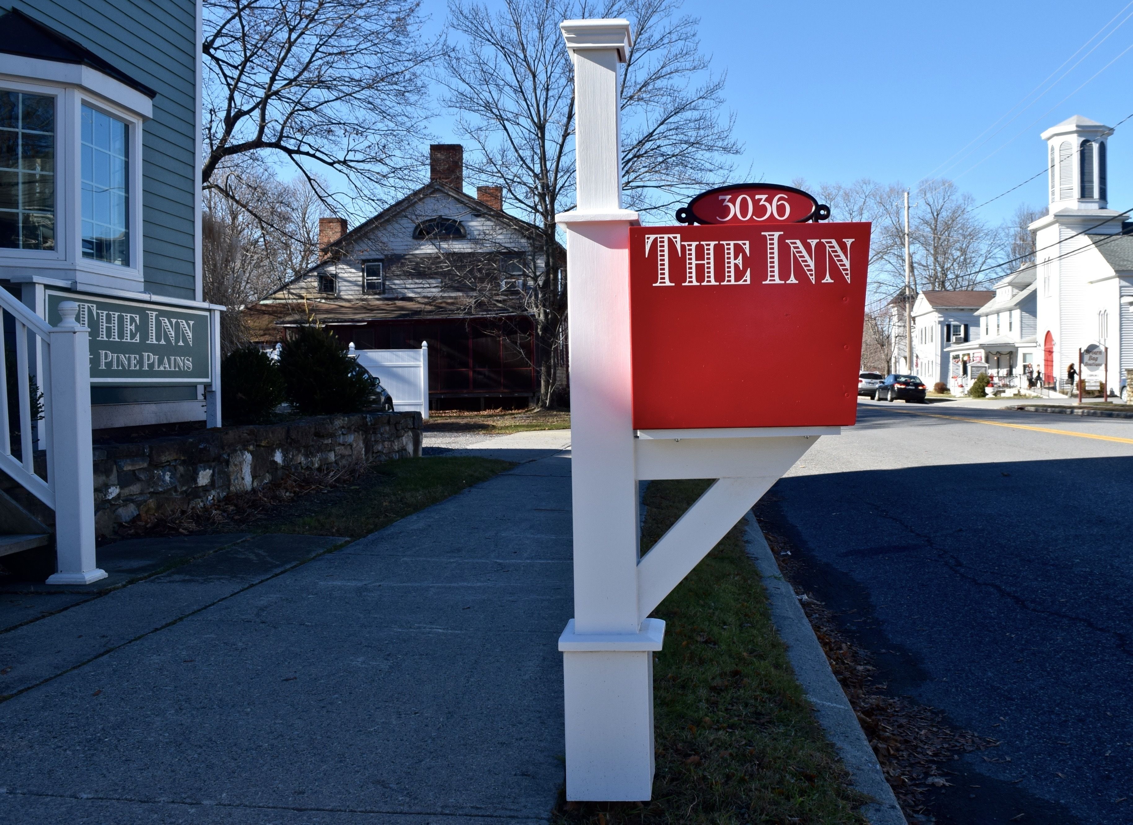 Un buzón rojo con el número 3036 y el texto "THE INN" en un poste blanco.