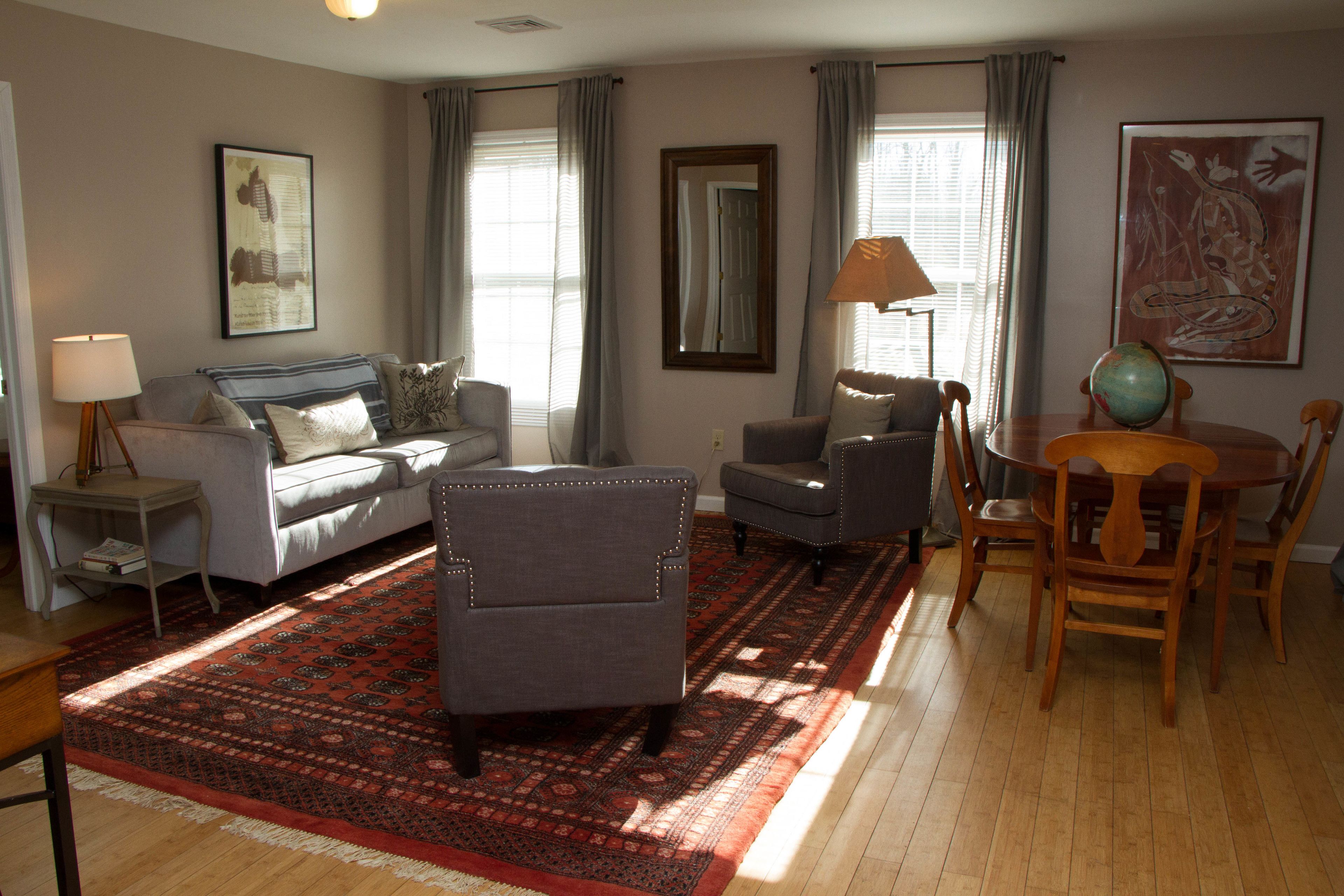 A living room with a sofa, armchairs, a coffee table, and a dining table with chairs.