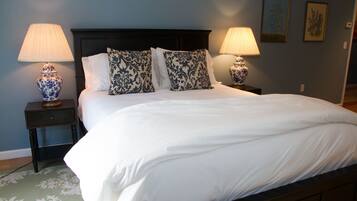 A neatly made bed with white linens, two decorative pillows, and two bedside lamps with blue and white patterns.