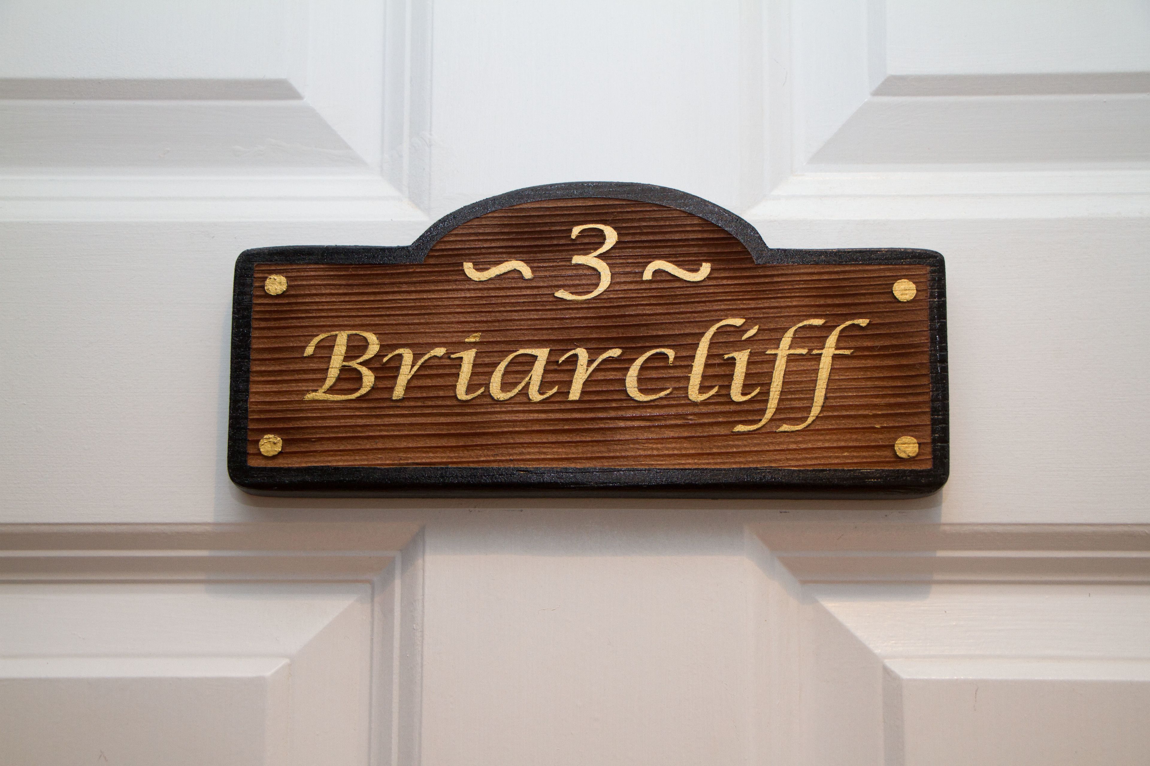 Una placa de madera con el número 3 y el nombre 'Briarciff' en una puerta blanca.