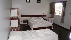 Ein Schlafzimmer mit einem hölzernen Bett, einem Nachttisch aus Holz, einem Spiegel und einem Fenster mit Vorhängen.