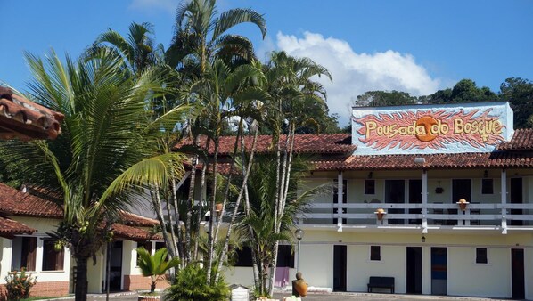 A building with a sign reading 'Pousada do Bosque' and a balcony with a view of palm trees. - Pousada Do Bosque (Itajuipe)