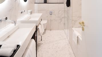 A modern bathroom with three sinks, a toilet, a shower, and a bathtub.