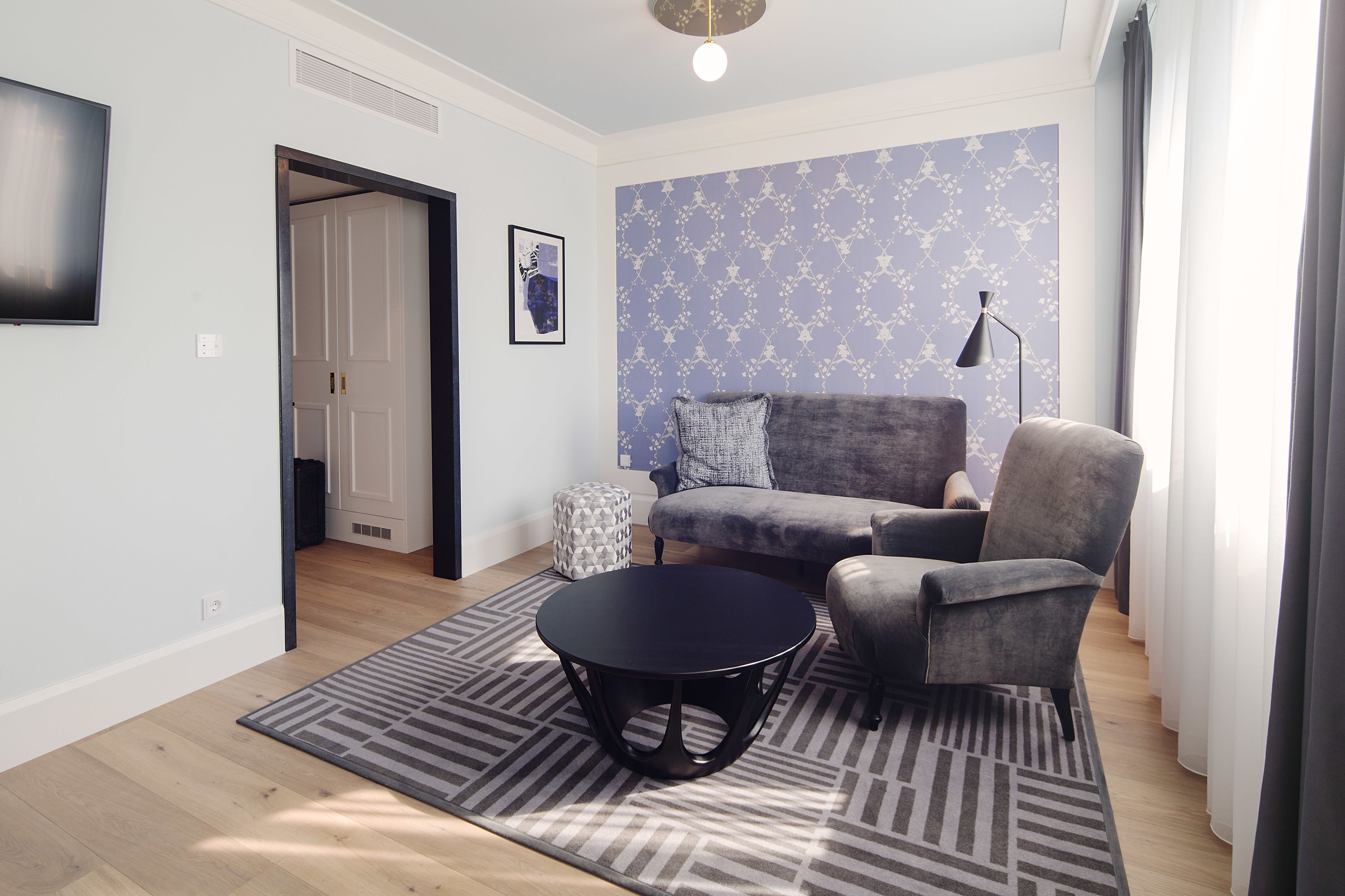 A living room with a grey sofa, a round black coffee table, and a patterned rug.