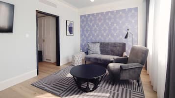 A living room with a grey sofa, a round black coffee table, and a patterned rug.