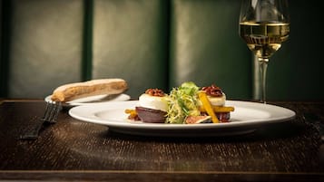 Un plato de comida con una copa de vino blanco sobre una mesa de madera.