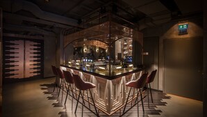 A bar area with a central bar counter, four bar stools, and a modern, illuminated design. - TORTUE HAMBURG (Hamburg)