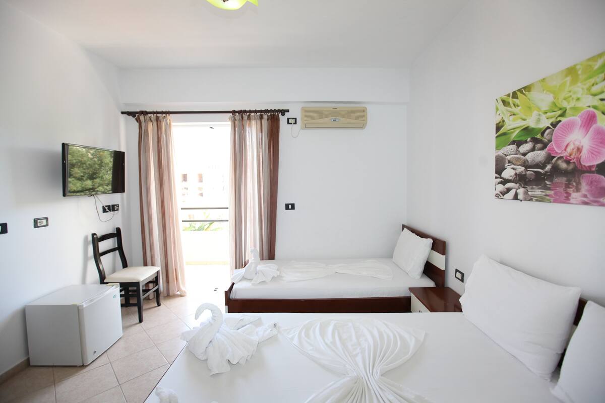 A hotel room with a bed, a chair, a TV, and a small refrigerator.