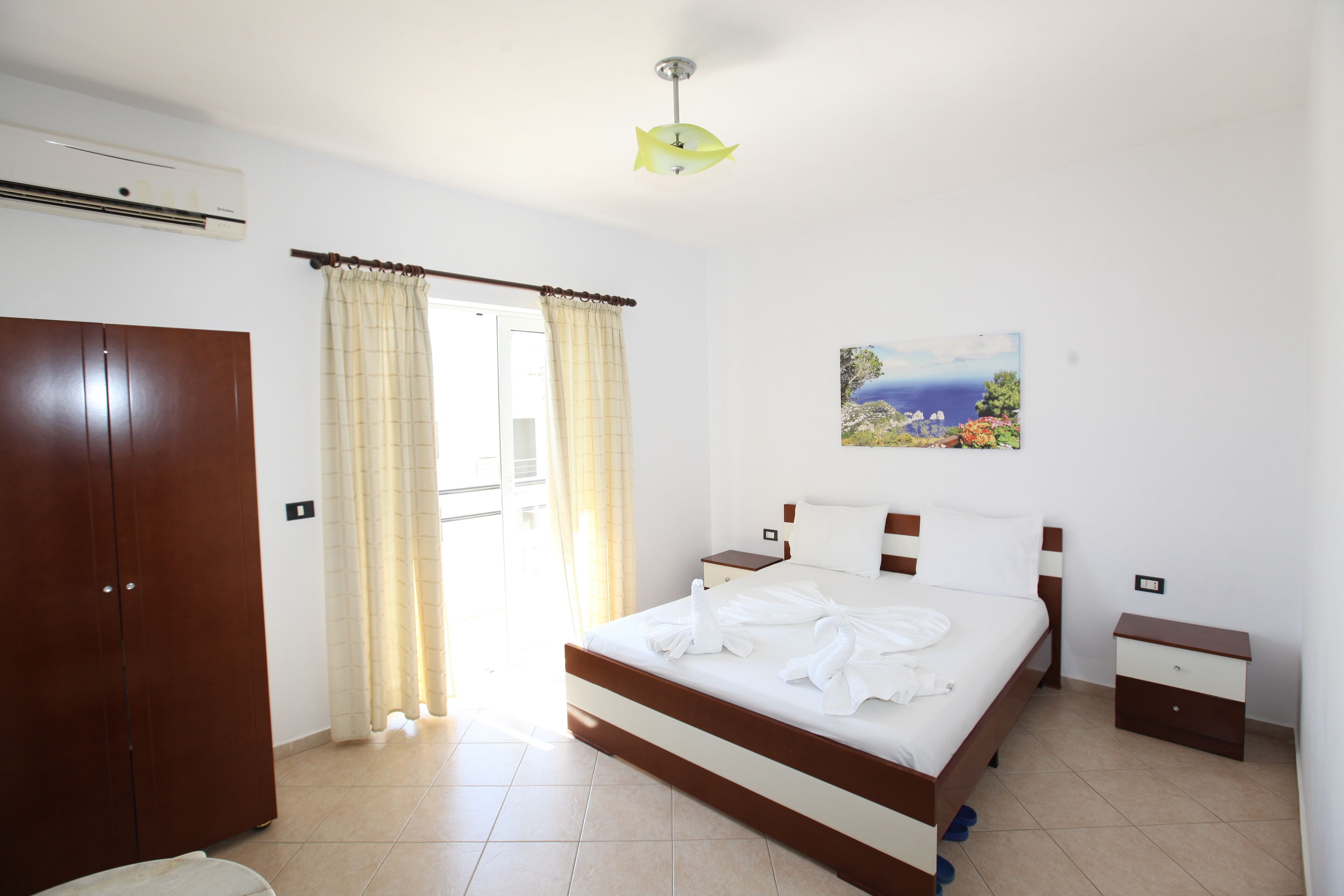 Une chambre d’hôtel avec un lit, une table de chevet, une armoire et un tableau au mur.