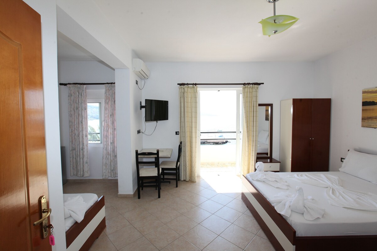 A hotel room with a bed, a desk, a chair, a television, and a window with curtains.