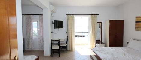A hotel room with a bed, a desk, a chair, a television, and a window with curtains.