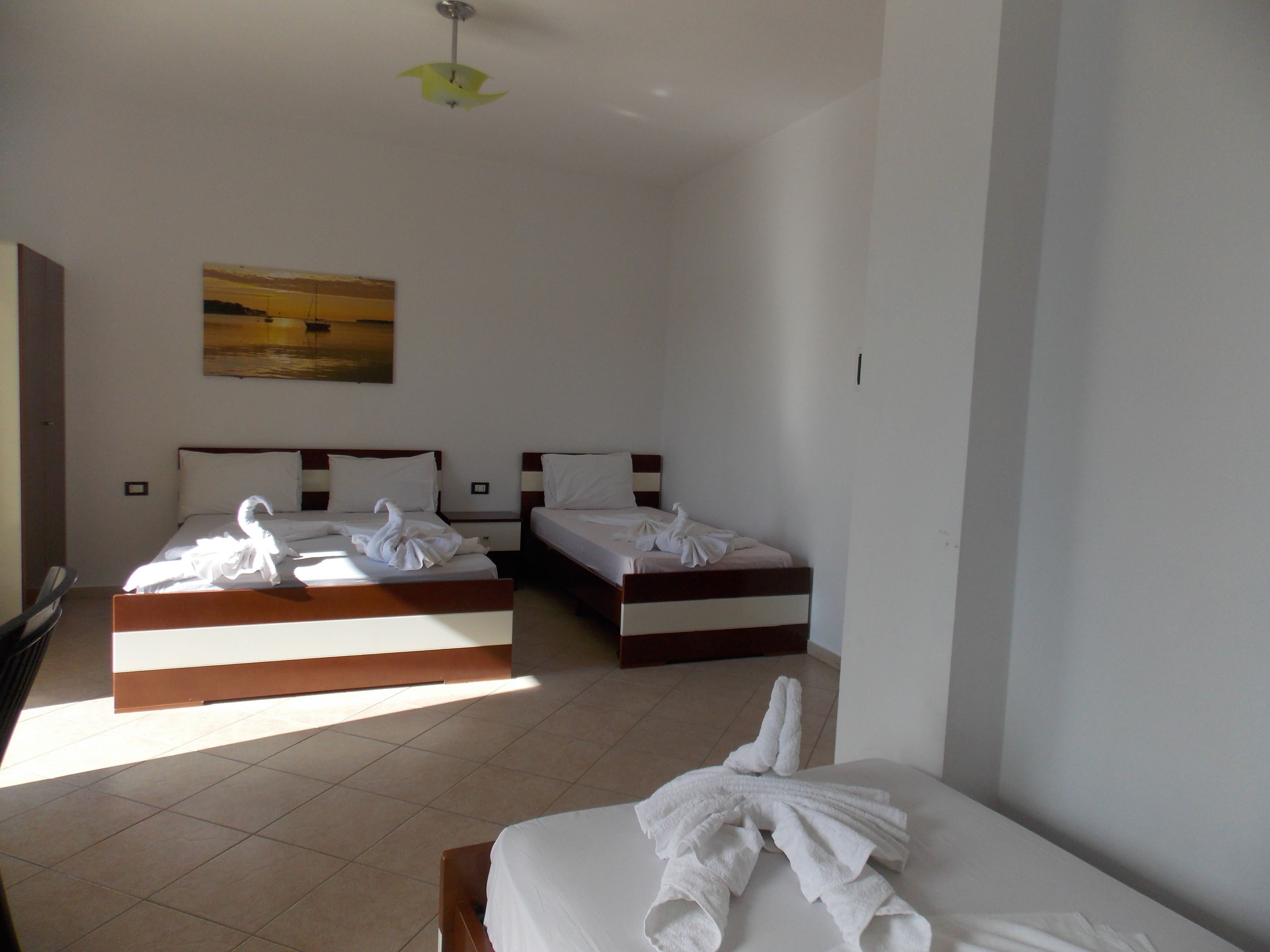 Ein Hotelzimmer mit zwei Betten, einem Bild an der Wand und einer Deckenleuchte.