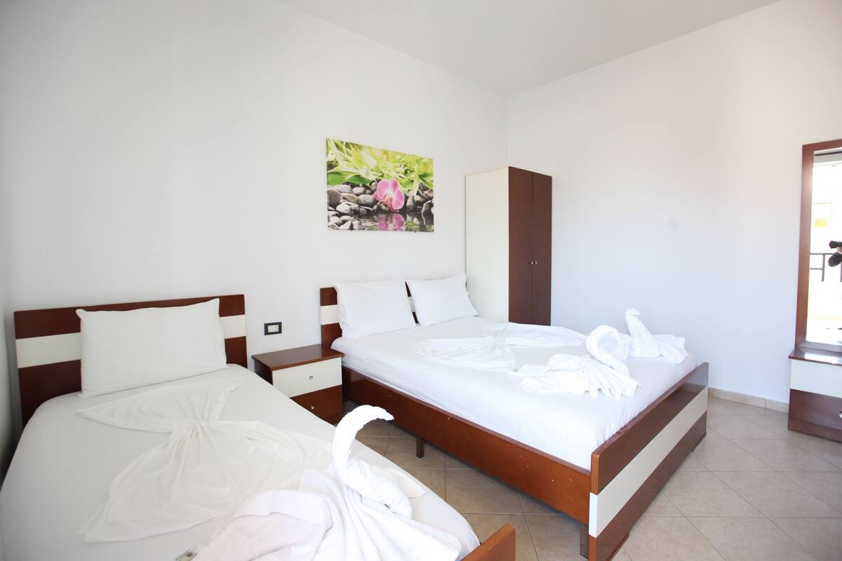 A hotel room with a bed, a nightstand, a wardrobe, and a painting on the wall.