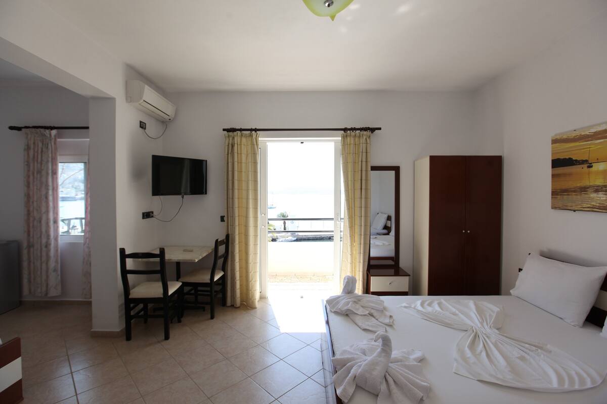 A hotel room with a bed, a desk, a chair, a TV, and a wardrobe.
